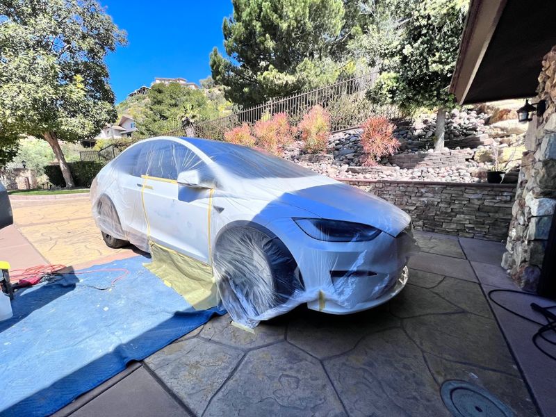 White Tesla Model X masked off for paint in a driveway